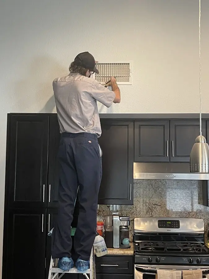 Technician inspecting an air vent during HVAC service in Fountainebleau